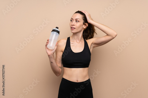 Young sport woman over isolated background with sports water bottle