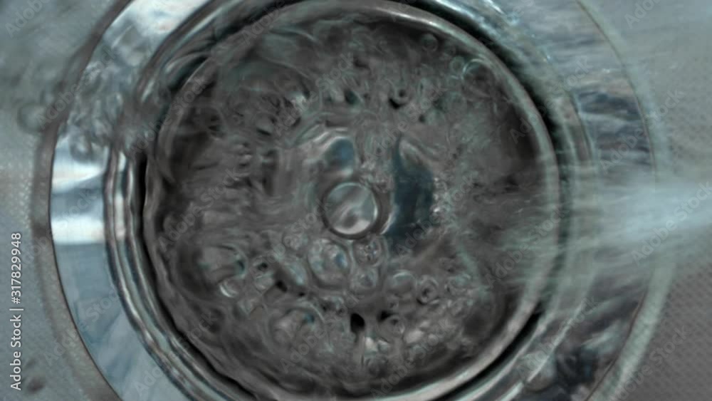 Streaming water in sink. Water stream going down the drain. Zoom in. Streaming water in sink. Water stream going down the drain. Zoom in.