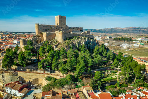 Aerial view of medieval Almansa castle with donjon and courtyard on a rock emerging from the plateau surrounded by a circular ring of red roof houses in Spain, site a famous battle