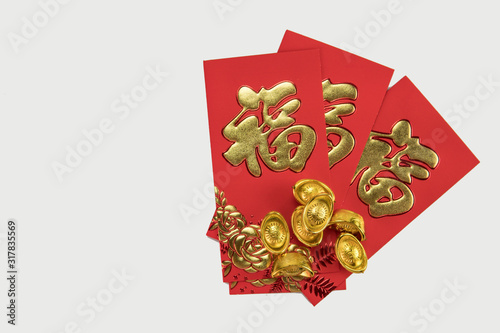 Flat lay of gold ingots and red angpow with Chinese character FU refer to fortune good luck, wealth, money flow on white background.