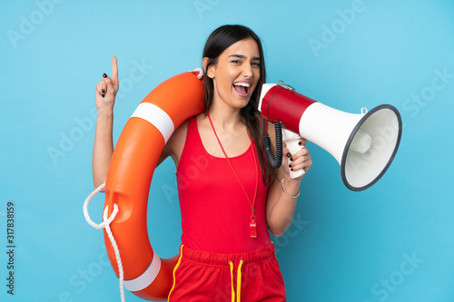 Lifeguard woman over isolated blue background with lifeguard equipment and shouting through a megaphone photo