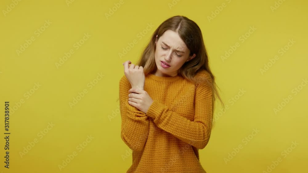 Hand damage, trauma. Sick unhappy young woman rubbing painful wrist, frowning suffering soreness, aching in sprained arm, carpal tunnel syndrome. indoor studio shot isolated on yellow background Hand damage, trauma. Sick unhappy young woman rubbing painful wrist, frowning suffering soreness, aching in sprained arm, carpal tunnel syndrome. indoor studio shot isolated on yellow background