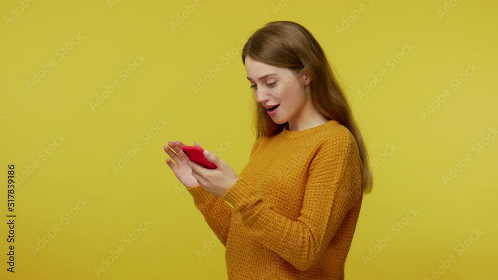 Surprised happy girl with kind friendly appearance scrolling social network posts on smartphone, saying wow, expressing amazement, user astonished by mobile phone. indoor studio shot yellow background Surprised happy girl with kind friendly appearance scrolling social network posts on smartphone, saying wow, expressing amazement, user astonished by mobile phone. indoor studio shot yellow background