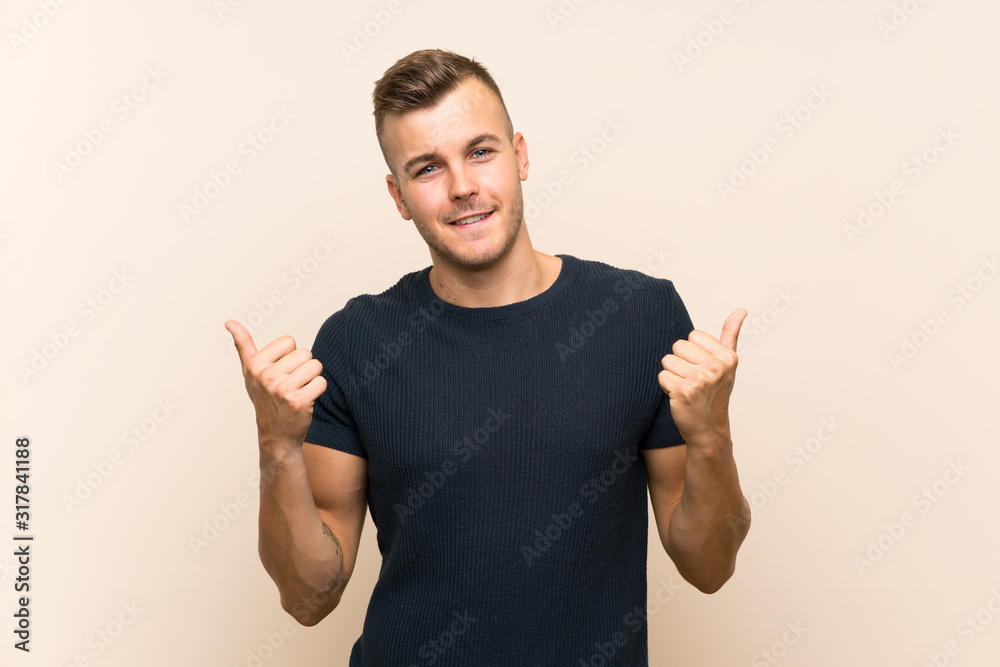 Young handsome blonde man over isolated background with thumbs up gesture and smiling Young handsome blonde man over isolated background with thumbs up gesture and smiling