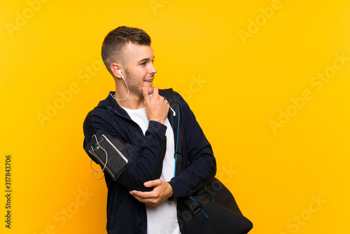 Young blonde sport man over isolated yellow background looking side