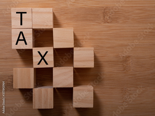 Tax with wooden alphabet blocks, on plank wooden background with copy space