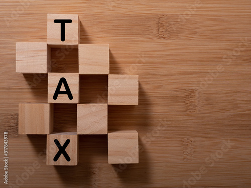 Tax with wooden alphabet blocks, on plank wooden background with copy space