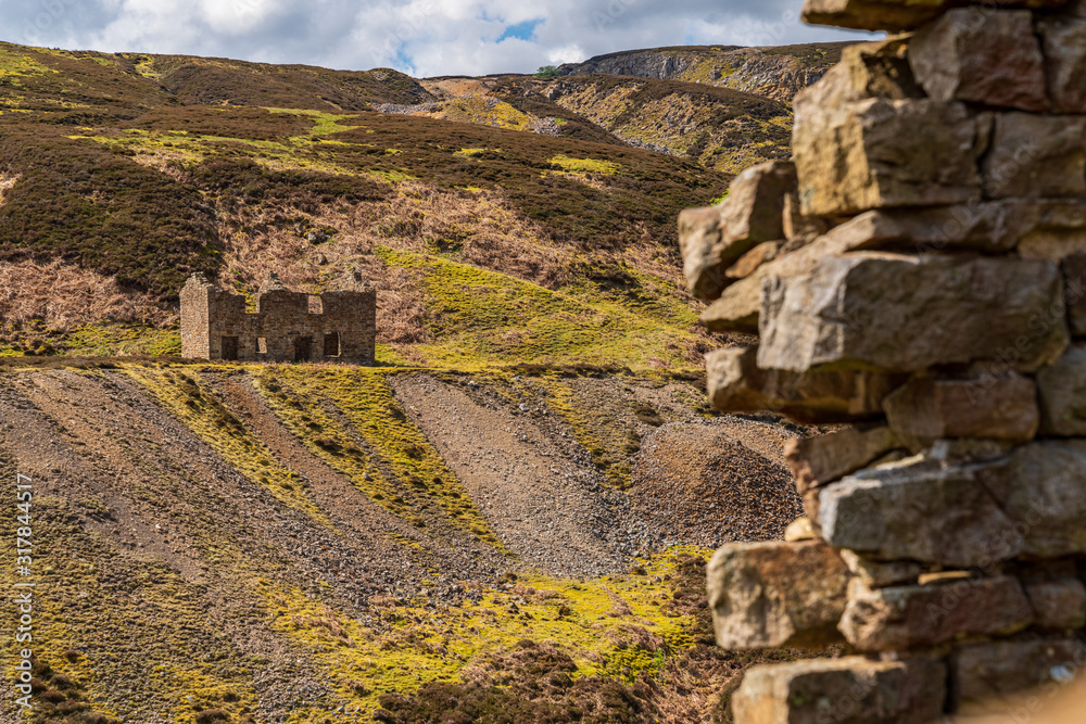 The remains of Bunton Mine with the Gunnerside Gill landscape, near Gunnerside, North Yorkshire, England, UK