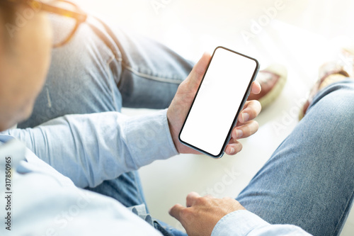 Mockup image blank white screen cell phone.men hand holding texting using mobile sitting on floor home.background empty space for advertise text.people contact marketing business and technology