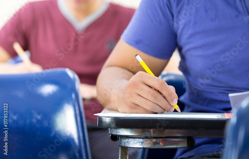 high school university student study.hands holding pencil writing paper answer sheet.sitting lecture chair taking final exam attending in examination classroom.concept scholarship for education abroad