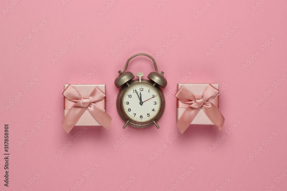 Retro alarm clock and gift boxes with bow on pink pastel background. 11:55 am. New Year, Christmas.concept. Top view Retro alarm clock and gift boxes with bow on pink pastel background. 11:55 am. New Year, Christmas.concept. Top view