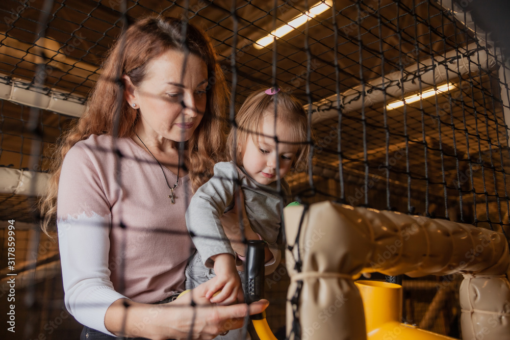 Mom and daughter enthusiastically shoot with a toy gun in the children's entertainment center