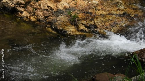 Crystal clear fresh mountain waterfall crocodile river water sparkling and flowing over rocks and pebbles in the background at the walter sisulu national botanical gardens in roodepoort, South Africa. photo