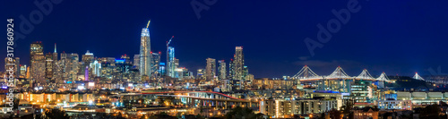 San Francisco skyline night panorama with city lights, the Bay Bridge and trail lights