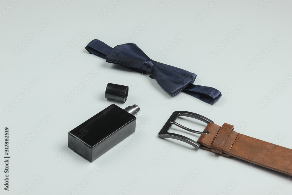 Bow tie, belt, perfume bottle on white background. Gents accessories. Formal style, preparing for the wedding. Bow tie, belt, perfume bottle on white background. Gents accessories. Formal style, preparing for the wedding.