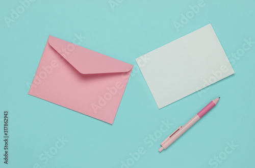 Envelope with a letter and pen on a blue pastel background. Valentine's day, wedding or birthday. Top view