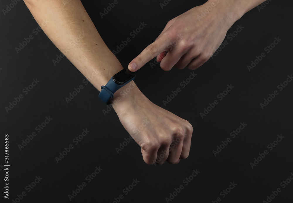 Female hand with a smart bracelet on a black background. Modern gadgets