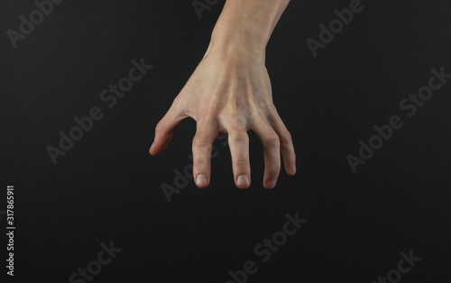 Female hand reaches for something on a black background