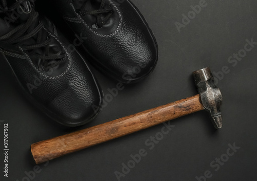 Work leather shoes and hammer. Industrial working tools and instruments, safety equipmen on black background. Top view