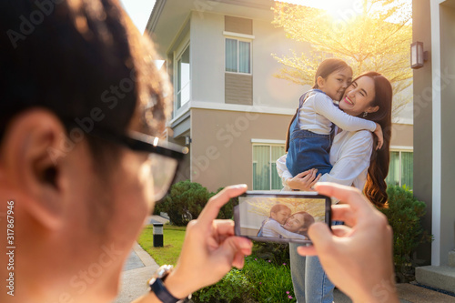 Father take a picture a mother and daughter in new house with sun set by he smart phone,, this photo canuse for family, fathe, mother and home concept photo