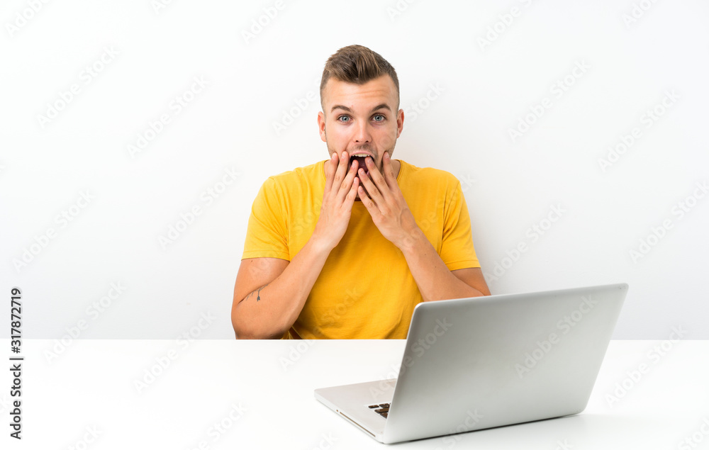 Young blonde man in a table with a laptop with surprise facial expression Young blonde man in a table with a laptop with surprise facial expression