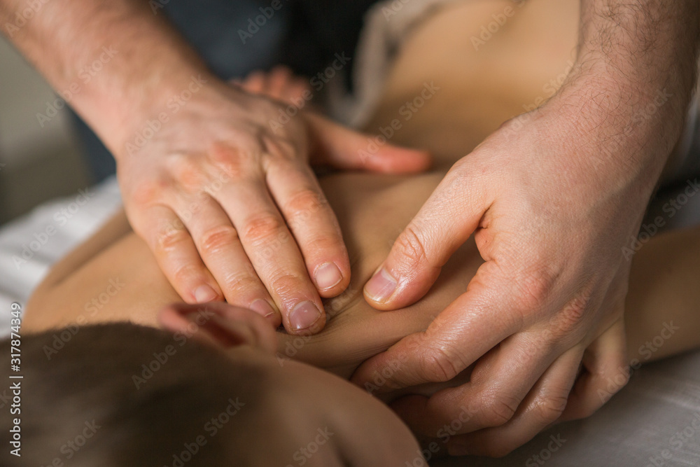 Boy toddler relaxes from a therapeutic massage. Physiotherapist working with patient in clinic to the back of a child