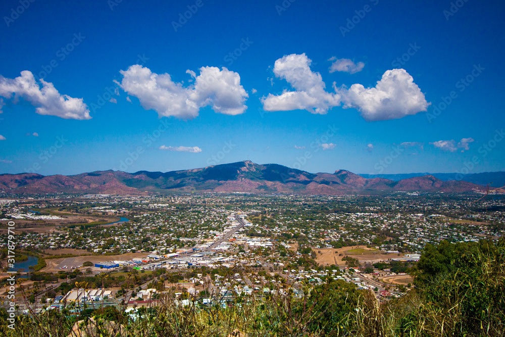 Scenic view from the Castle Hill Lookout at Townsville (Queensland, Australia) with a mountain on the horizon and clouds in the sky.