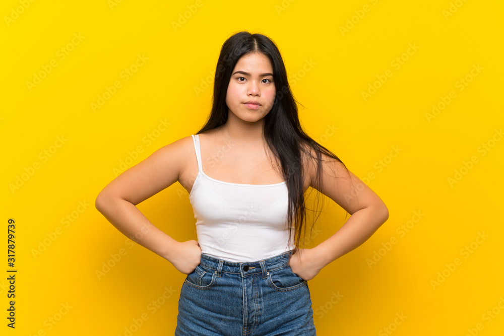 Young teenager Asian girl over isolated yellow background angry Young teenager Asian girl over isolated yellow background angry