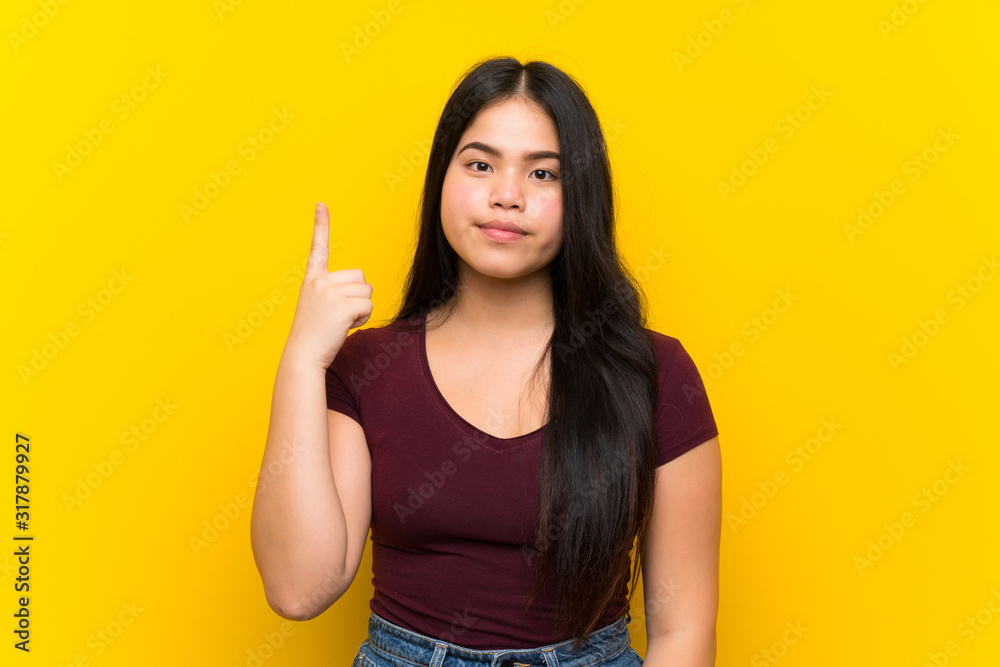 Young teenager Asian girl over isolated yellow background pointing with the index finger a great idea Young teenager Asian girl over isolated yellow background pointing with the index finger a great idea