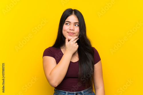 Young teenager Asian girl over isolated yellow background thinking an idea