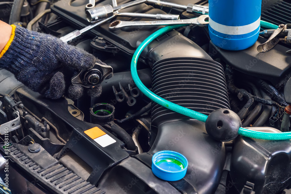 hand of Mechanic check water in car radiator and add water antIfreeze