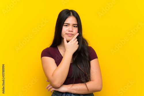 Young teenager Asian girl over isolated yellow background thinking an idea © luismolinero
