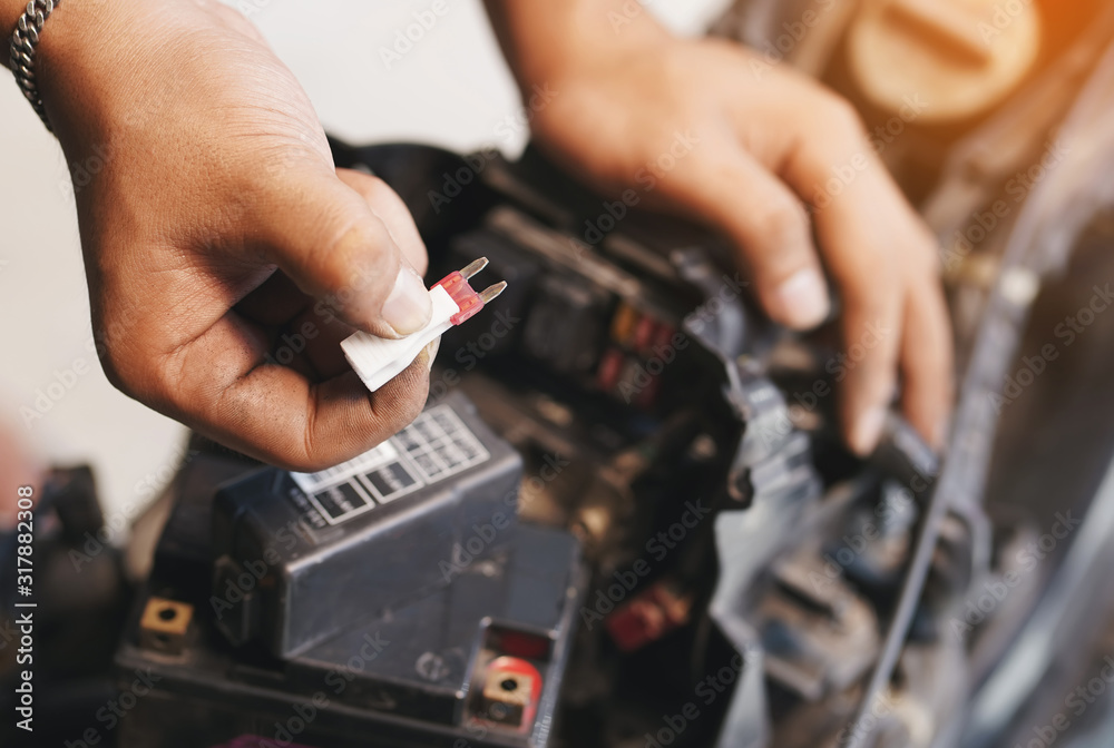 motorcycle mechanic replaces a fuse battery. motorcycle maintenance and service and repair concept , selective focus motorcycle mechanic replaces a fuse battery. motorcycle maintenance and service and repair concept , selective focus