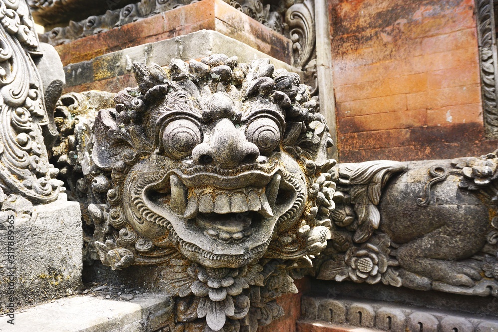 Antique smiling demon sculpture at a temple in Bali Indonesia