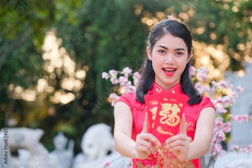 Asian girl in the red dress of Chinese descent is happy with the red envelope with the dollar