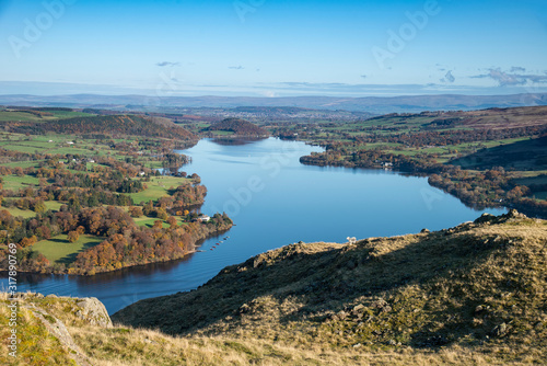 Fototapeta Naklejka Na Ścianę i Meble -  Beautiful Autumn Fall landscape of Ullswater and surrounding mountains and hills viewed from Hallin Fell on a crisp cold morning with majestic sunlgiht on the hillsides