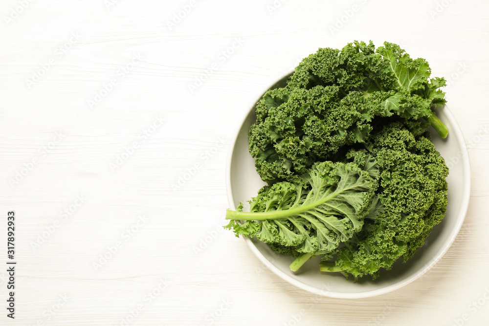 Fresh kale leaves on white wooden table, top view. Space for text