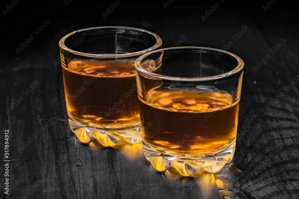 two glasses of cognac on a black tree