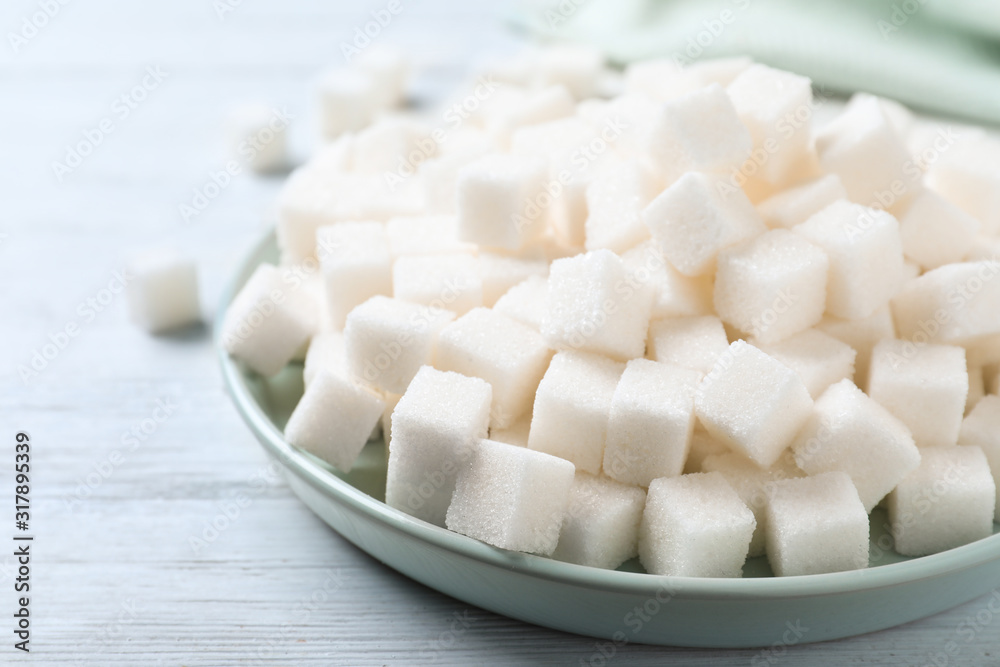 Refined sugar cubes on white wooden table, closeup