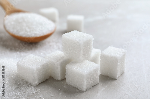 Heap of refined sugar cubes on light grey table, closeup