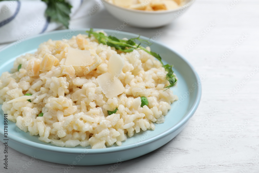 Delicious risotto with cheese on white wooden table, closeup