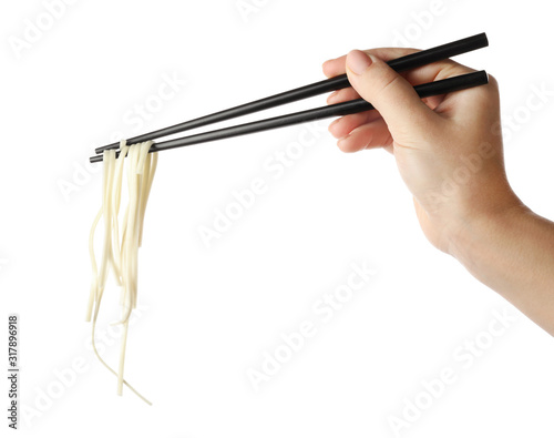 Woman holding chopsticks with tasty cooked rice noodles on white background, closeup photo