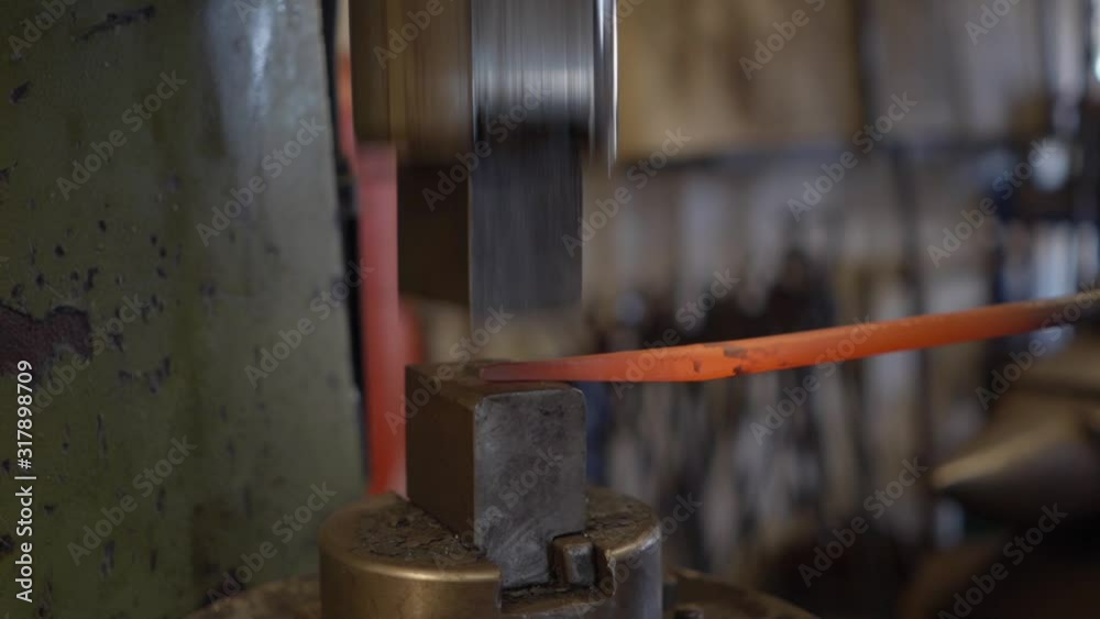 Industrial hydraulic hammer forging a hot steel piece in a workshop. Industrial hydraulic hammer forging a hot steel piece in a workshop.
