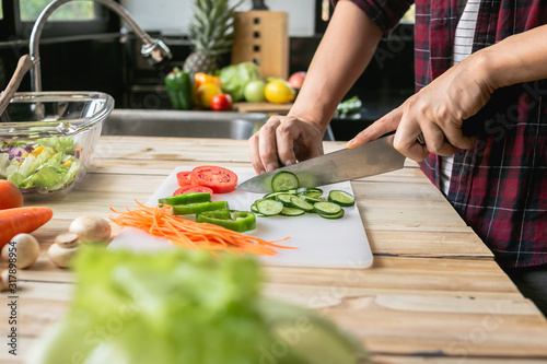 Close-up man cooking and slicing fresh vegetables on a rustic kitchen worktop, healthy eating concept, flat lay