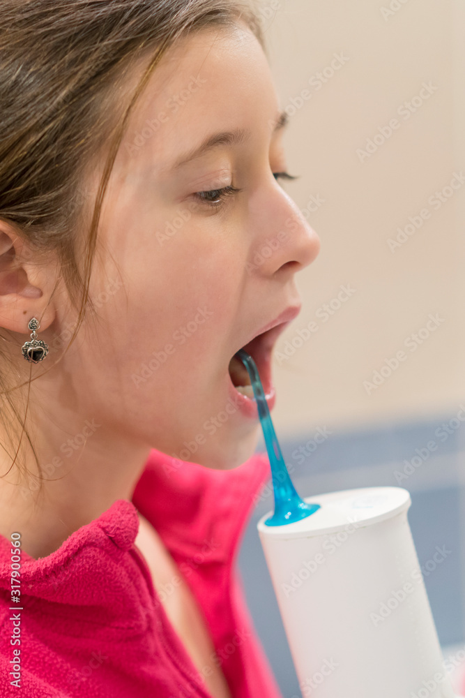 A girl cleaning her teeth with oral irrigator. A girl using an oral irrigator in bathroom. Dental Care Concept. Oral Care Concept. vertical photo A girl cleaning her teeth with oral irrigator. A girl using an oral irrigator in bathroom. Dental Care Concept. Oral Care Concept. vertical photo