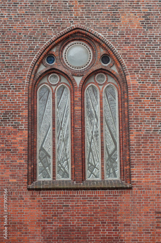 Brick wall of the Church with beautiful arched stained glass window. Beautiful architecture. Details.