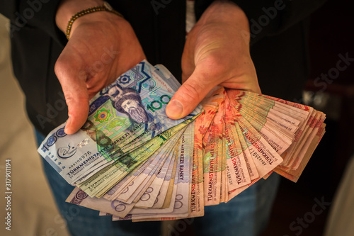 Valokuva Tourist holding a collection of Turmenistan Manat exchanged for dollars on the black market at the Russian bazaar