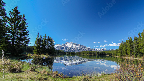 Early morning view from Two Jack Lake in Rocky mountains Canada Alberta Rockies with mountain reflecting mirror in water with blue skies 