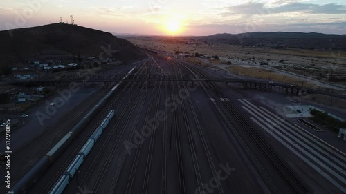 Aerial over railroad yard and tracks towards bridge into setting sun, Barstow photo