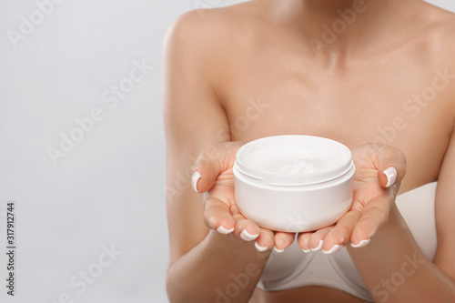 Fototapeta Naklejka Na Ścianę i Meble -  Beauty Concept. Woman holds a moisturizer cosmetic cream in her hand. Skin care. Soft skin and naked shoulders